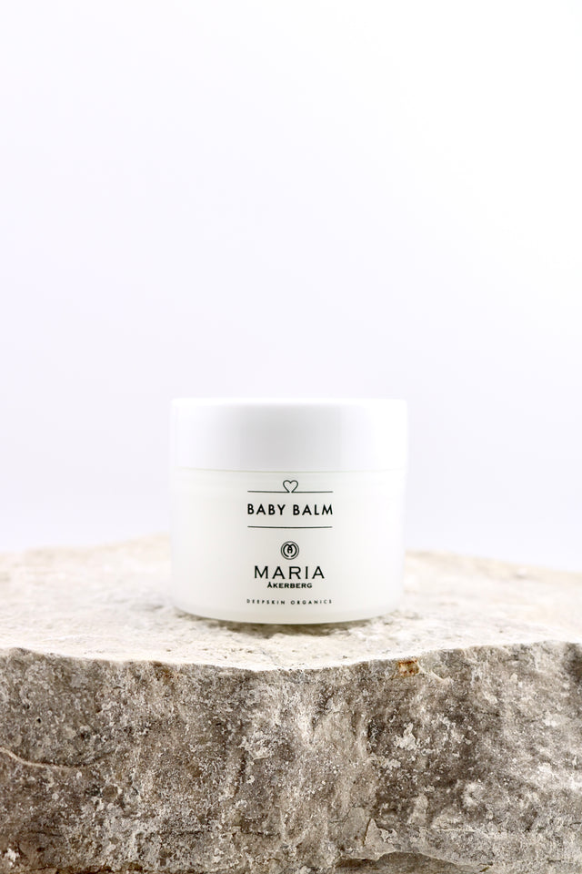 White jar of baby balm labeled 'Maria Åkersberg baby balm' on a stone surface with a white background