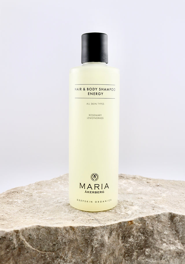Shampoo bottle labeled 'Hair & Body Shampoo Energy' by Maria Åkerberg on a stone surface with a white background