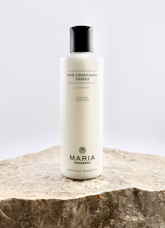 Hair conditioner bottle labeled 'Maria Åkerberg' on a stone surface with a light gray background