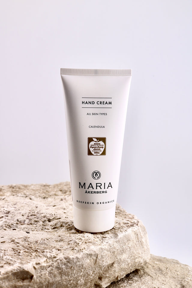 Hand cream tube labeled 'Maria Åkerberg' on a textured stone surface with a light gray background