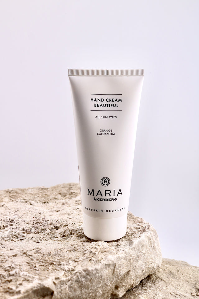 Hand cream tube labeled 'MARIA' on a textured stone surface with a light gray background