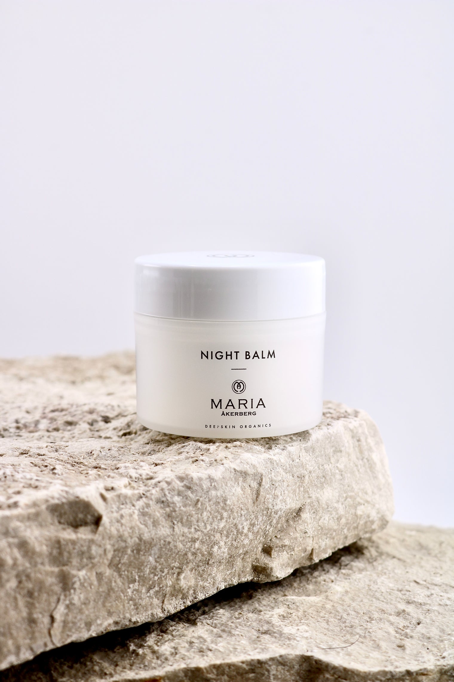 Jar of night balm labeled 'Maria' on a stone surface with a light gray background