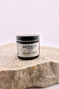 Jar of Acrely Farms Recovery Balm on a stone surface with a white background