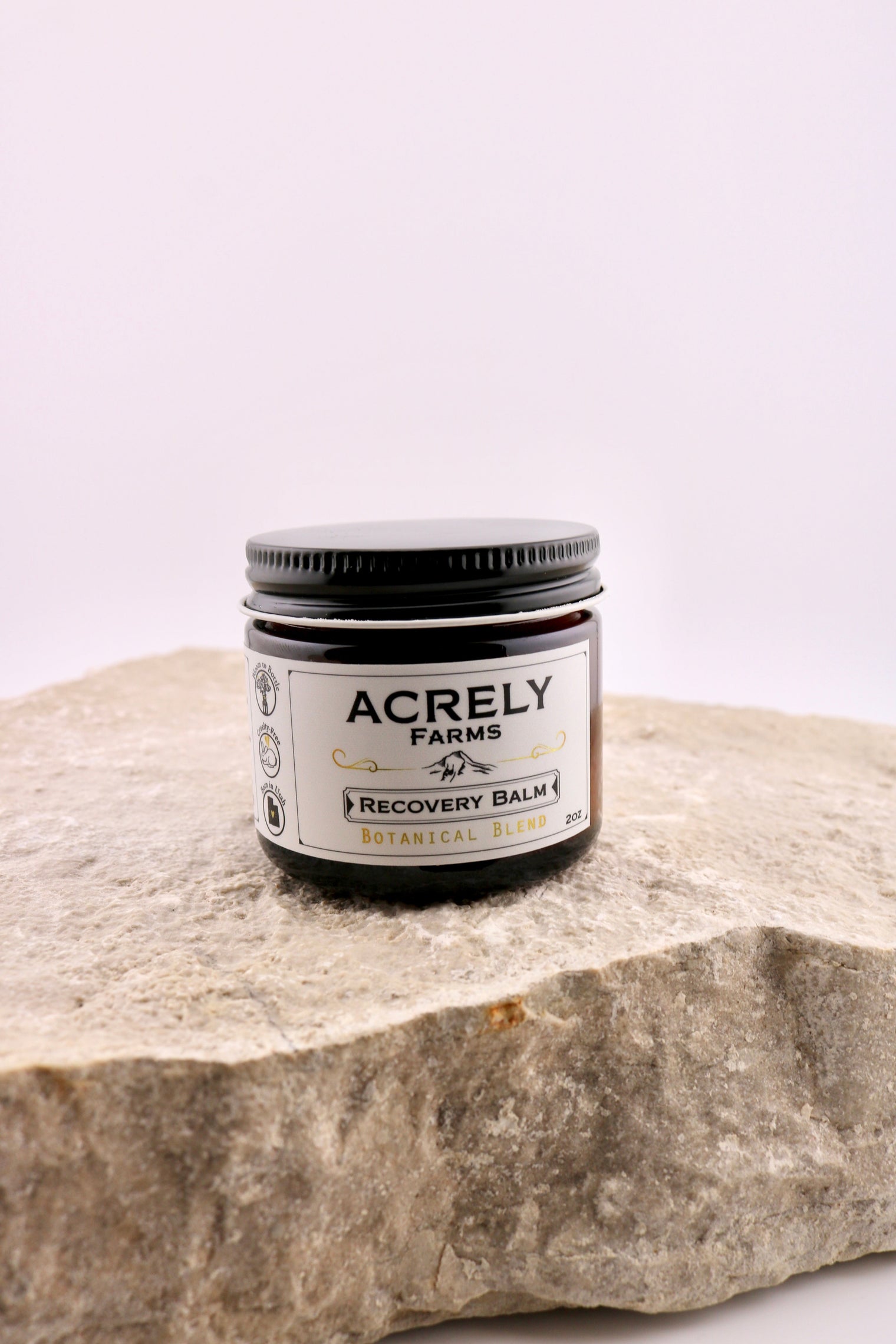 Jar of Acrely Farms Recovery Balm on a stone surface with a white background