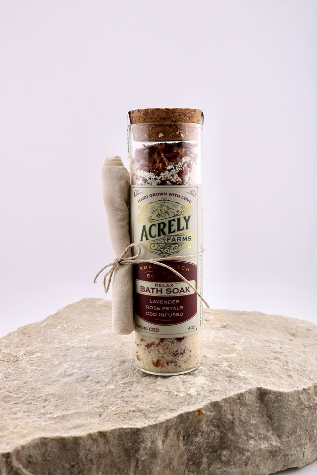 Bottle of Acrely Farms bath soak on a stone surface with a white background