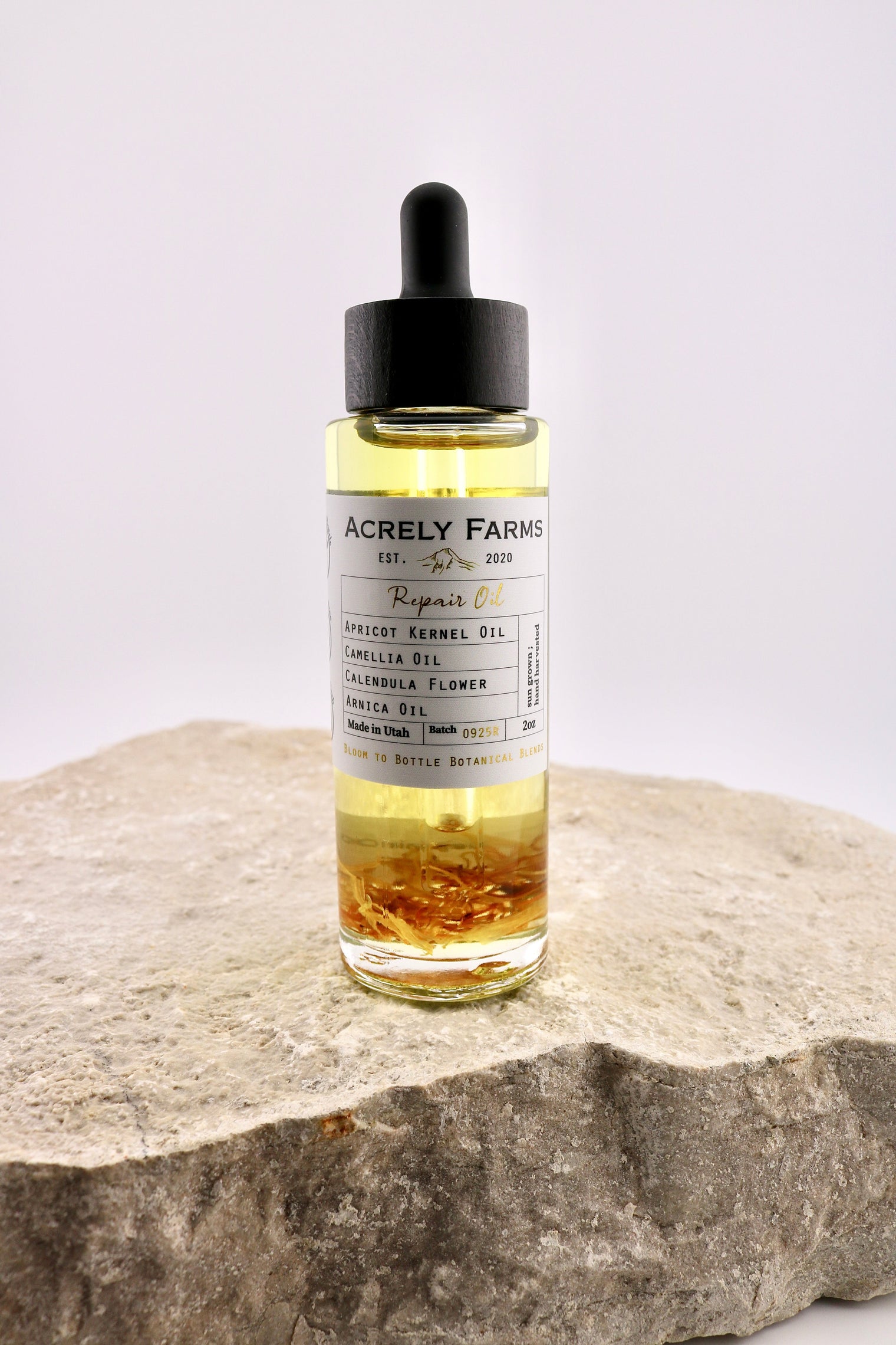 Bottle of Acrely Farms repair oil on a stone surface with a white background