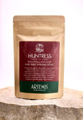 Tea package labeled 'Huntress' by Artemis on a wooden surface with a white background