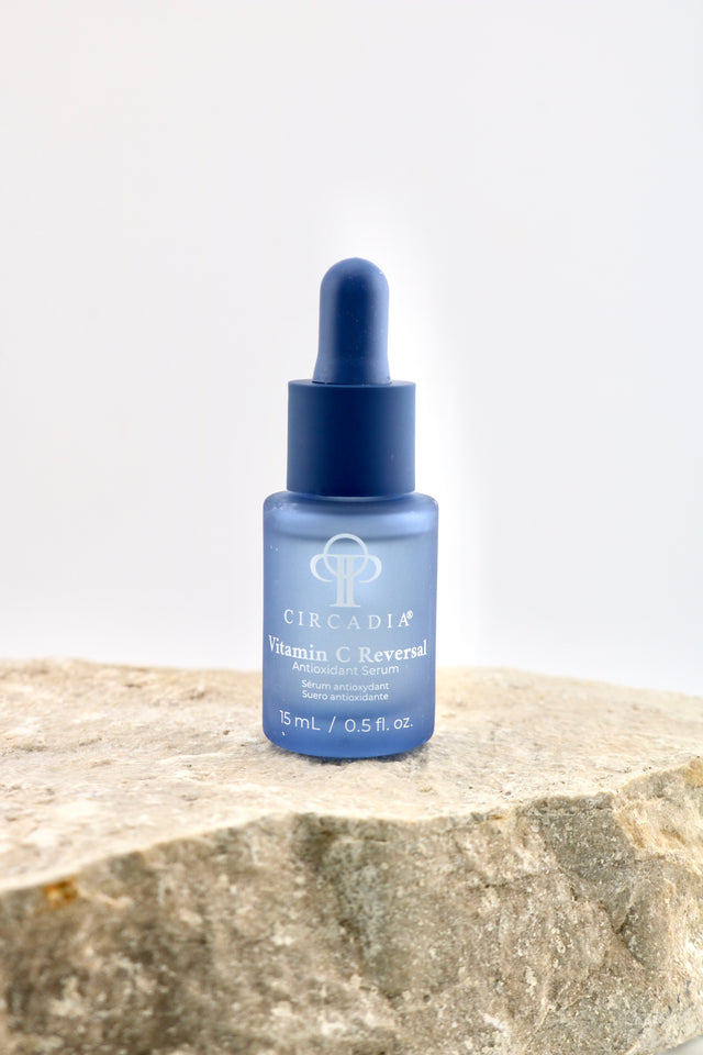 A blue glass dropper bottle of Circadia Vitamin C Reverse serum, displayed on a textured stone slab against a clean white background.