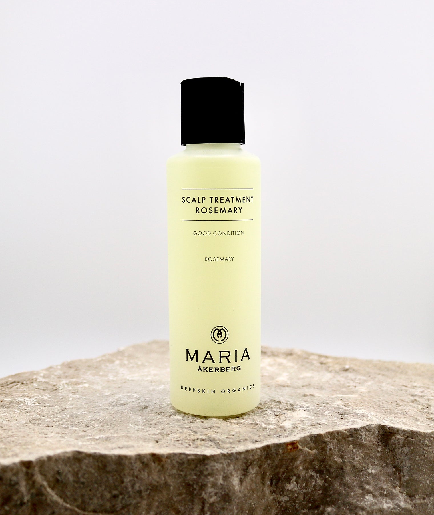Bottle of Maria Akerberg scalp treatment with rosemary on a stone surface