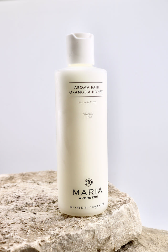 Bottle of Maria Åkerberg Aroma Bath Orange & Honey on a stone surface with a light gray background