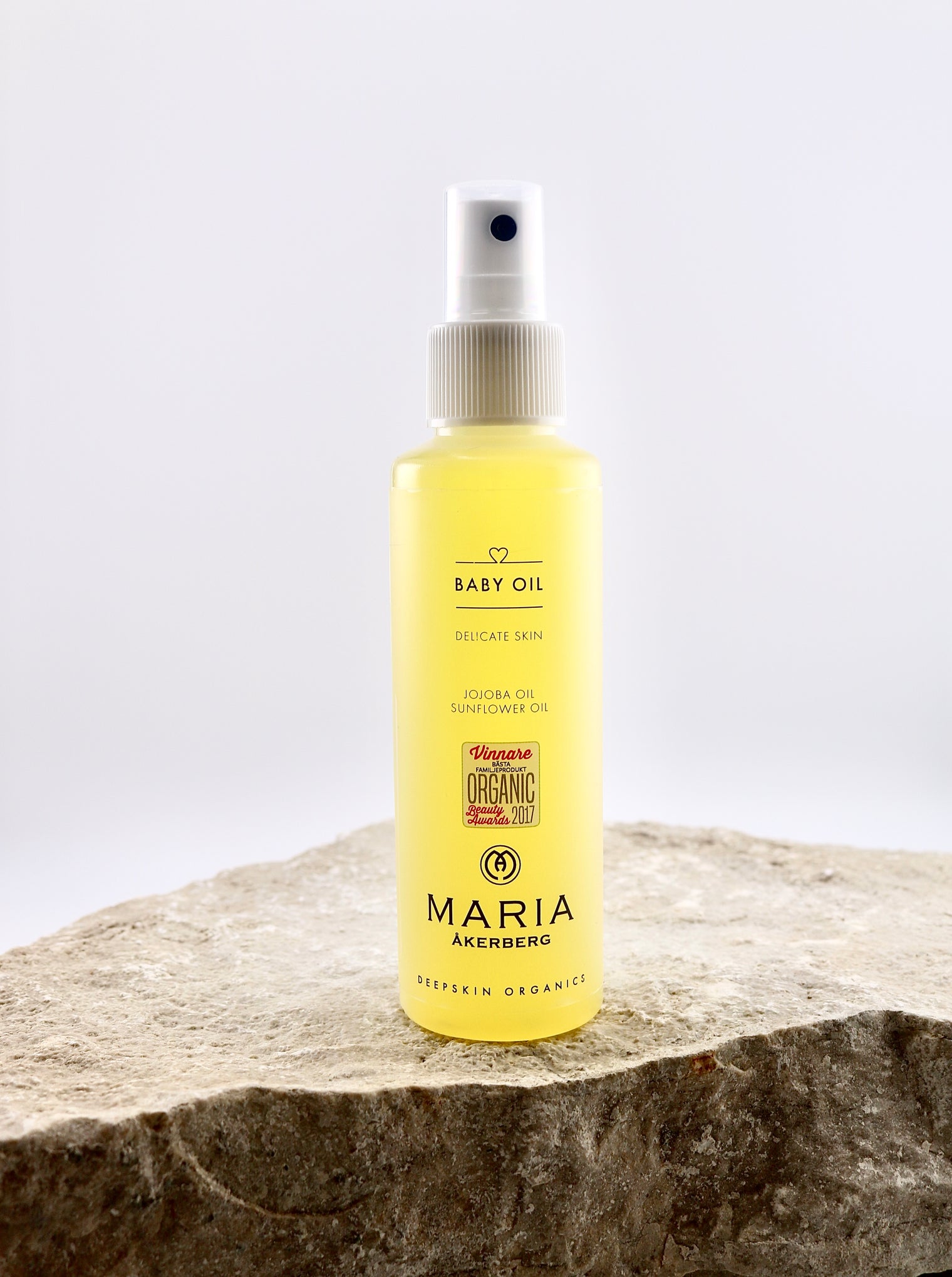 Yellow bottle of Maria Åkersberg baby oil on a stone surface with a white background
