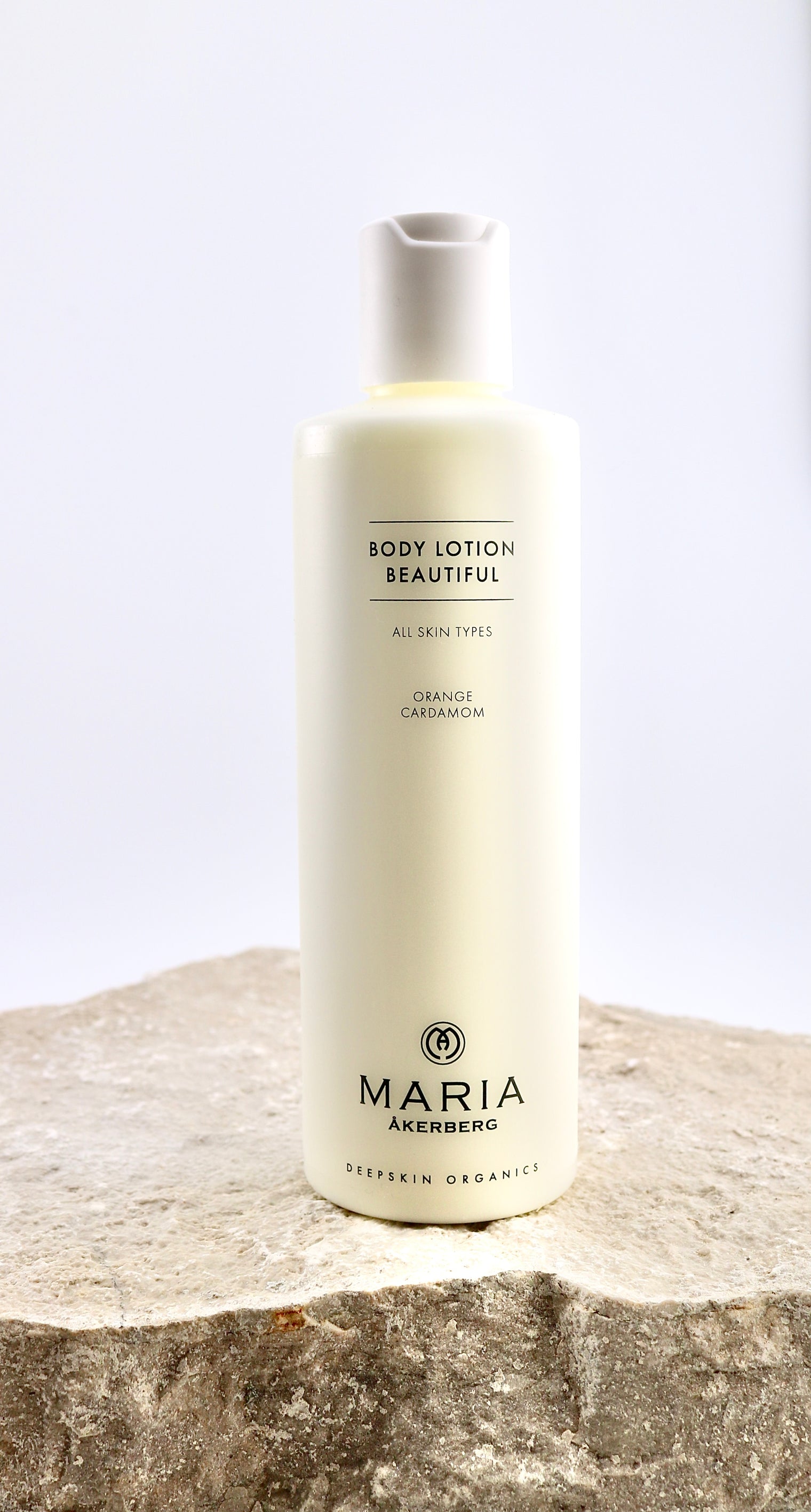 Bottle of Maria Åkerberg body lotion on a stone surface with a light background