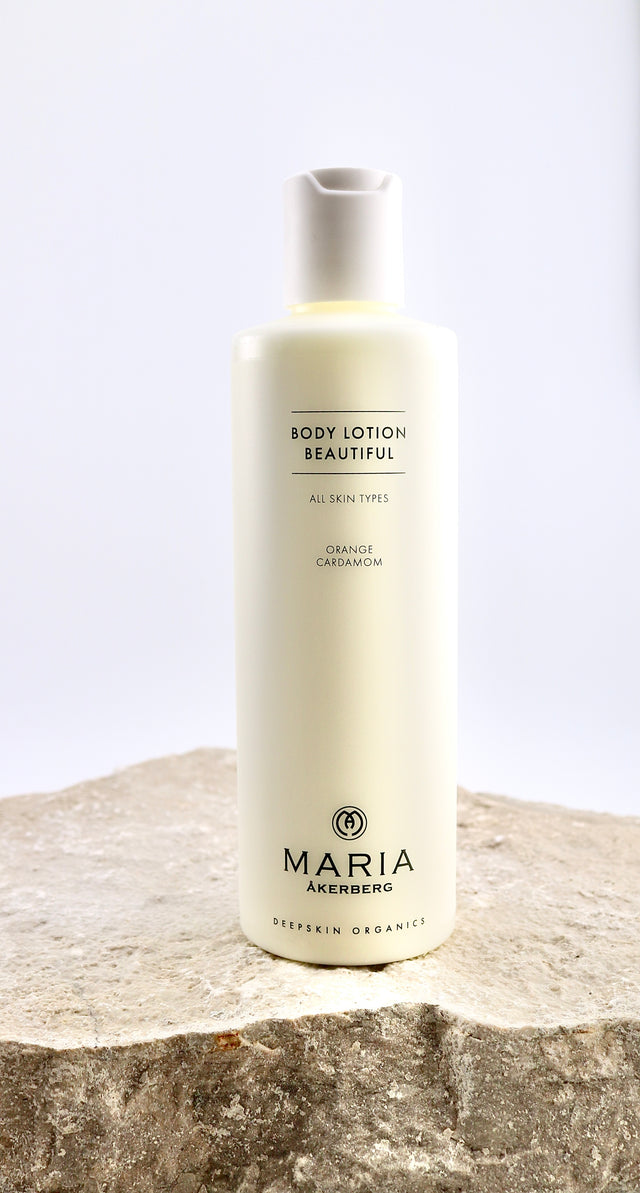 Bottle of Maria Åkerberg body lotion on a stone surface with a light background