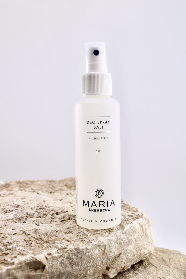 Deodorant spray bottle labeled 'Maria Akerberg' on a rock with a light gray background
