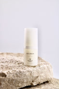 Eye cream bottle labeled 'MARIA' on a textured stone surface with a light gray background