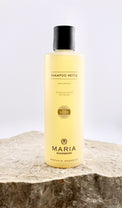 Shampoo bottle labeled 'Shampoo Nettle' by Maria Åkerberg on a stone surface with a white background