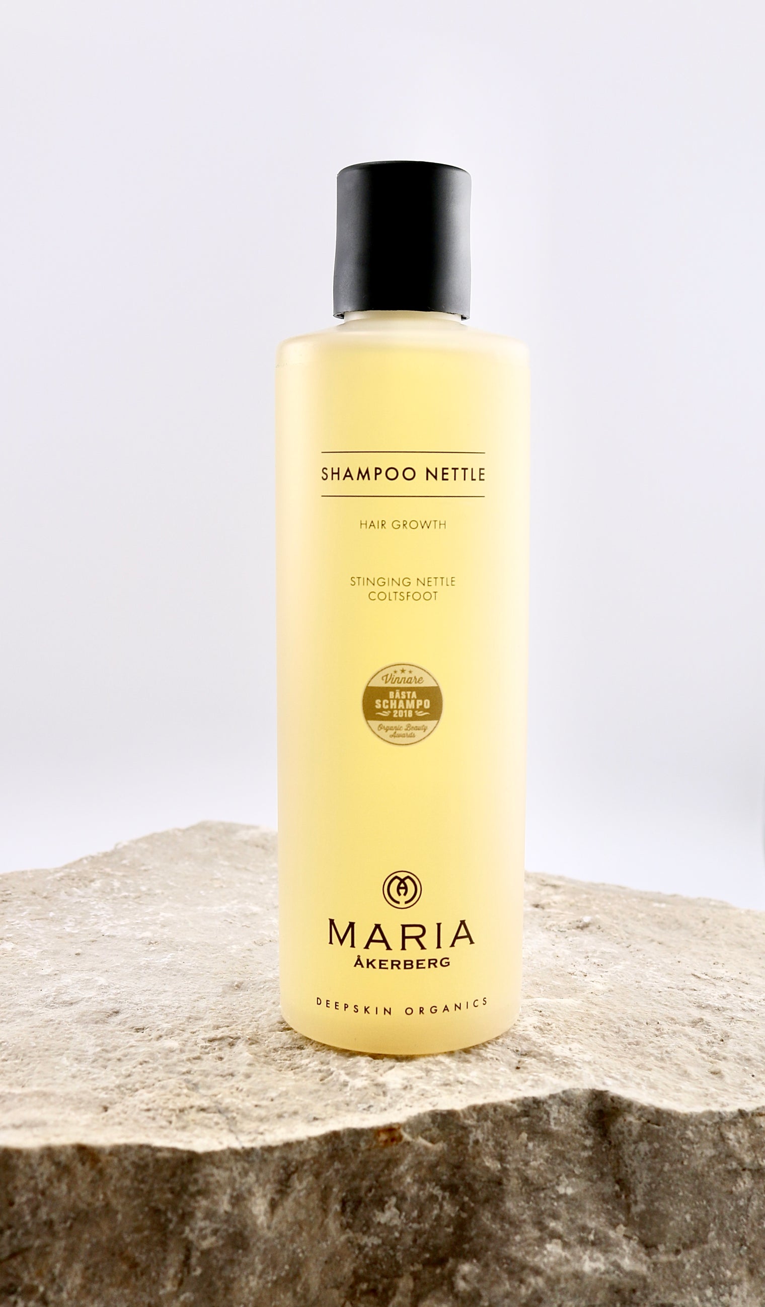 Shampoo bottle labeled 'Shampoo Nettle' by Maria Åkerberg on a stone surface with a white background