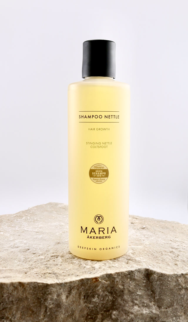Shampoo bottle labeled 'Shampoo Nettle' by Maria Åkerberg on a stone surface with a white background