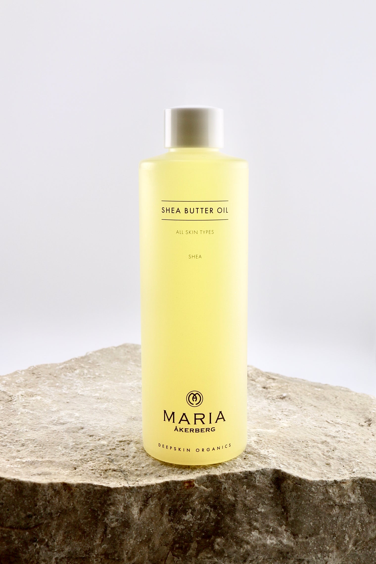 Bottle of Maria Åkerberg shea butter oil on a stone surface with a white background